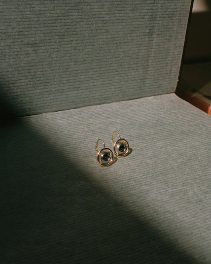 Gold earrings on a textured gray surface